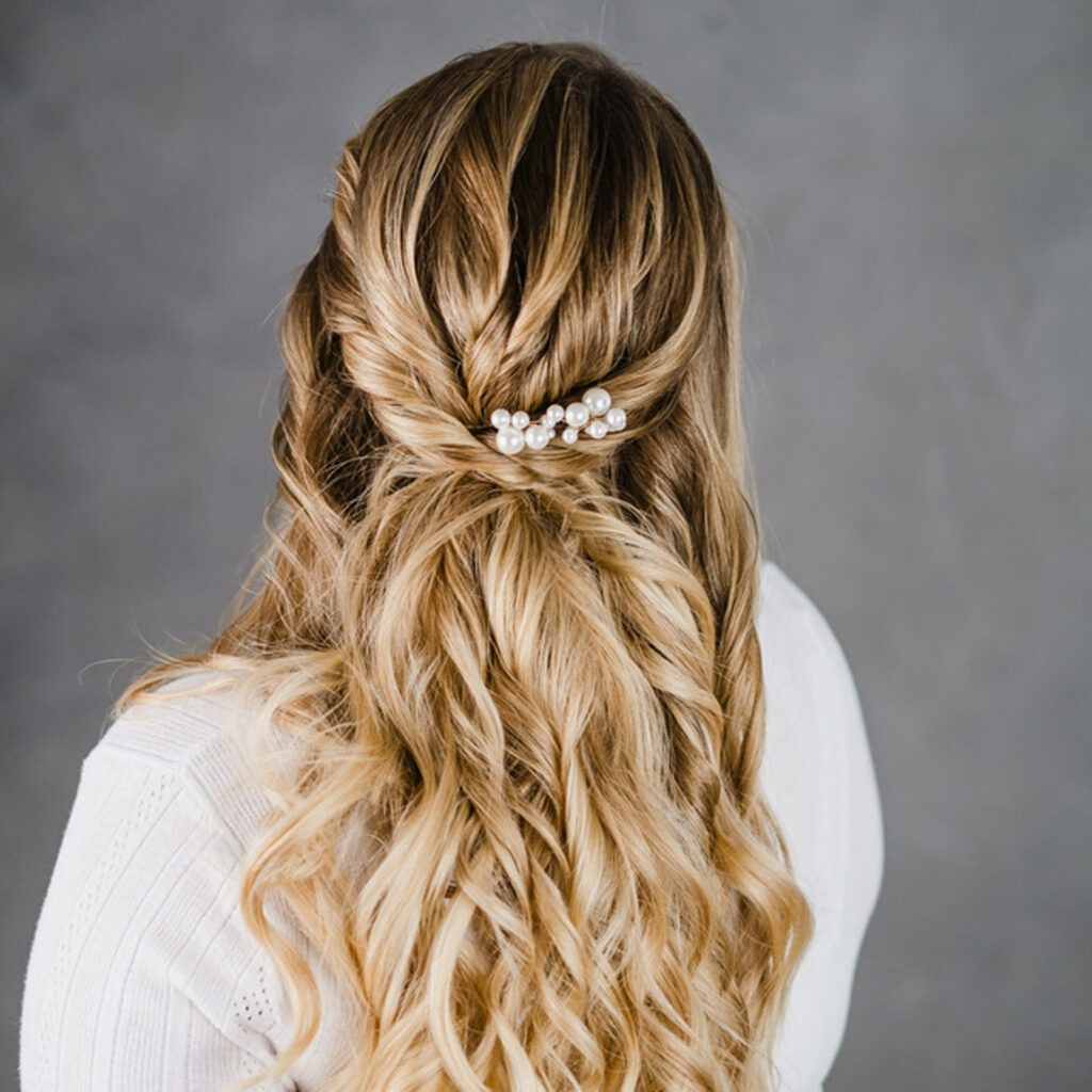 Halboffenes Hairstyling mit gekordelten seitlichen Elementen und Perlenschmuck.
